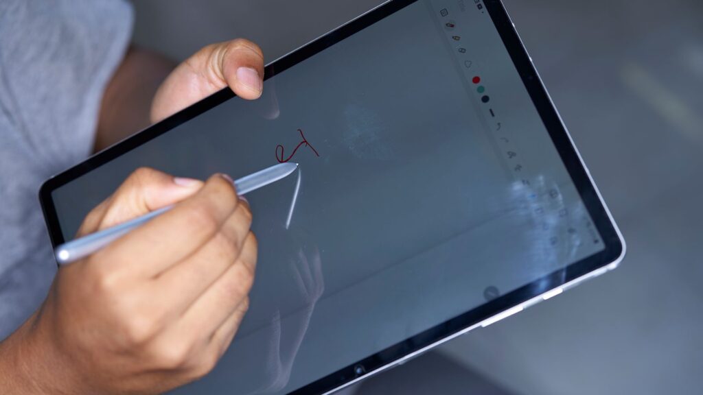Hand writing with a stylus on a tablet screen