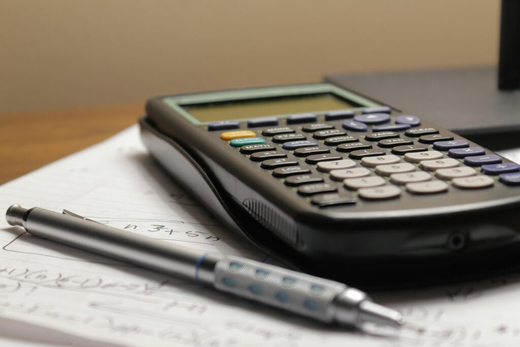 Scientific calculator and pen resting on handwritten budget notes