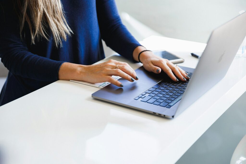 Hands typing on a laptop at a white desk