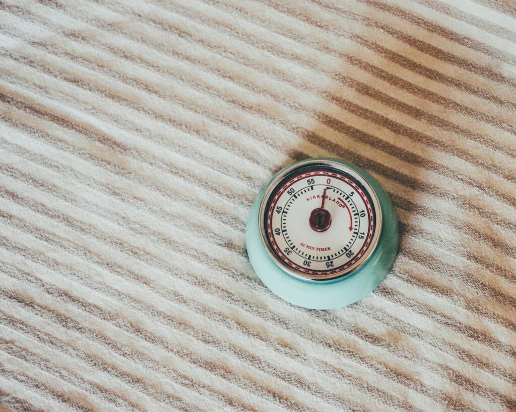 Round mint green kitchen timer lying on a striped fabric